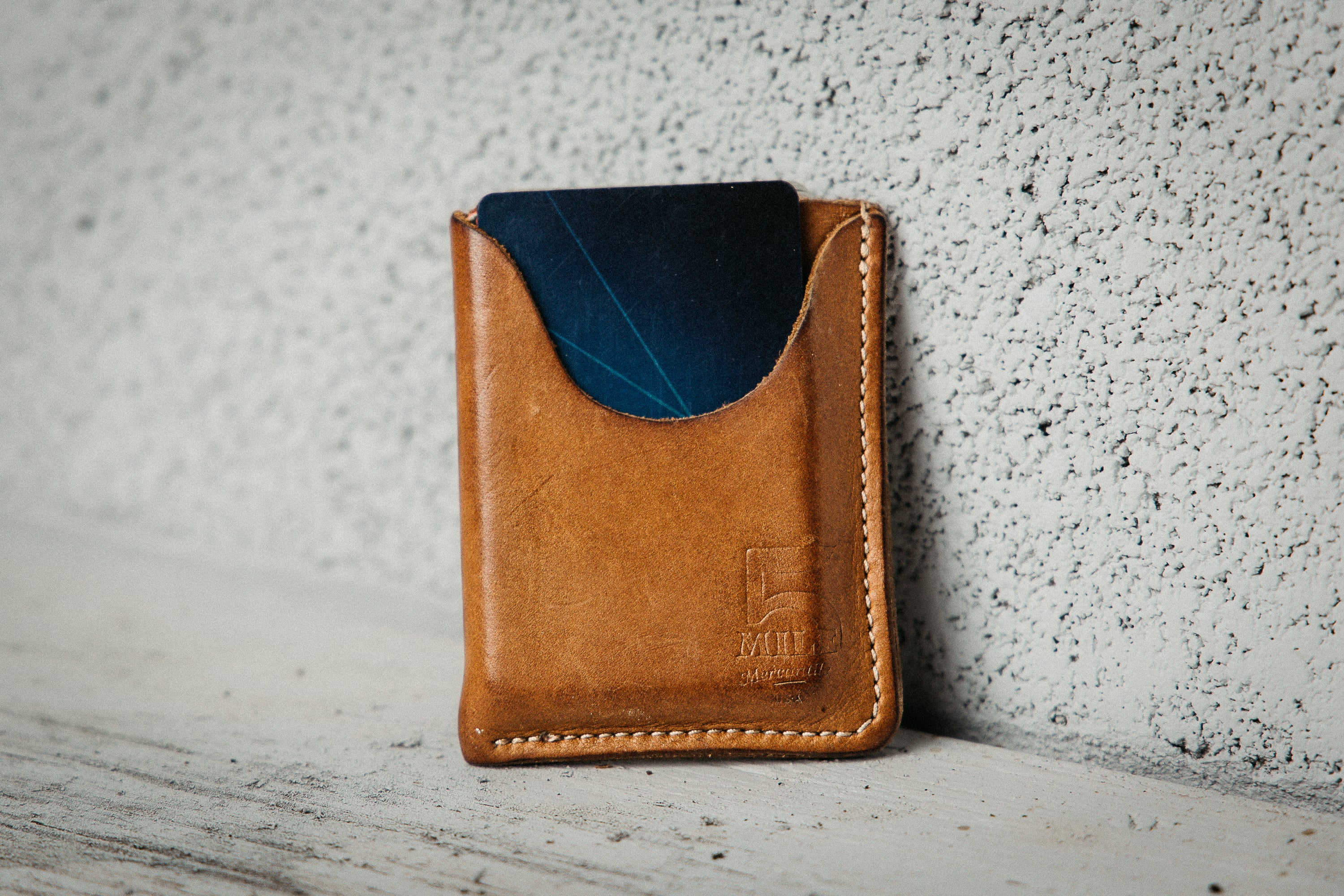 Brown leather wallet with blue interior on a textured surface