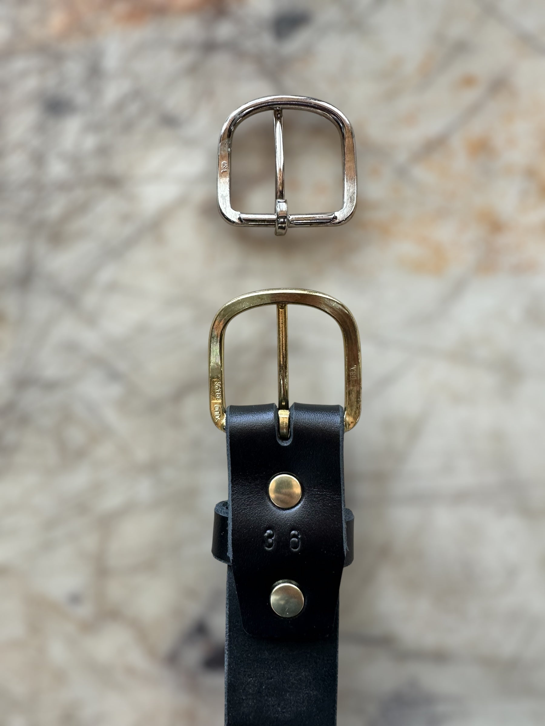 Black belt on cutting table with brass and silver buckle