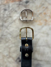 Black belt on cutting table with brass and silver buckle