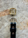 Two belt buckles, one gold and one silver, on a textured surface.