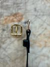 Gold buckle and black cord on a textured surface