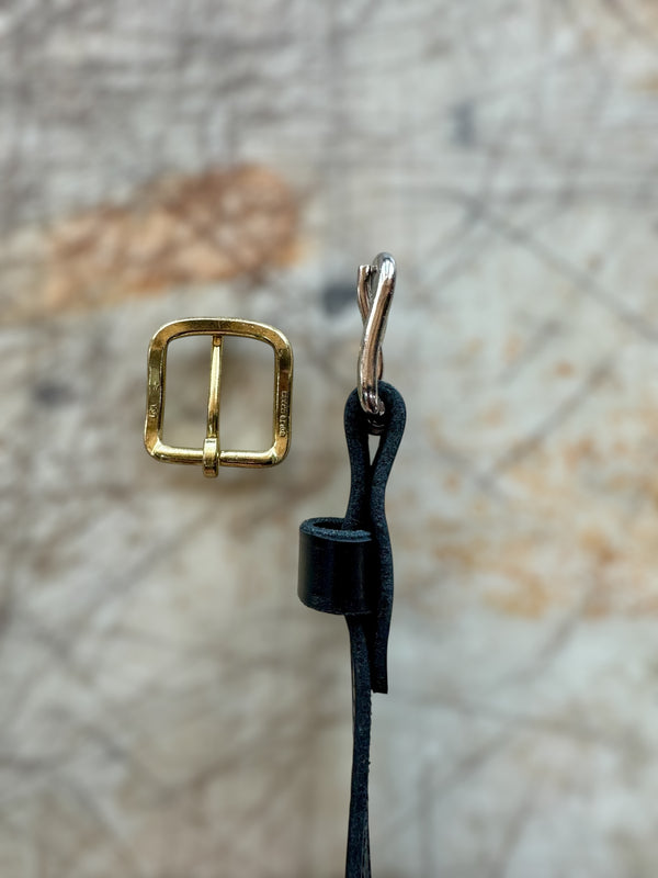 Gold buckle and black cord on a textured surface
