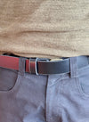 Close-up of a person wearing a black belt, green sweater, and grey pants