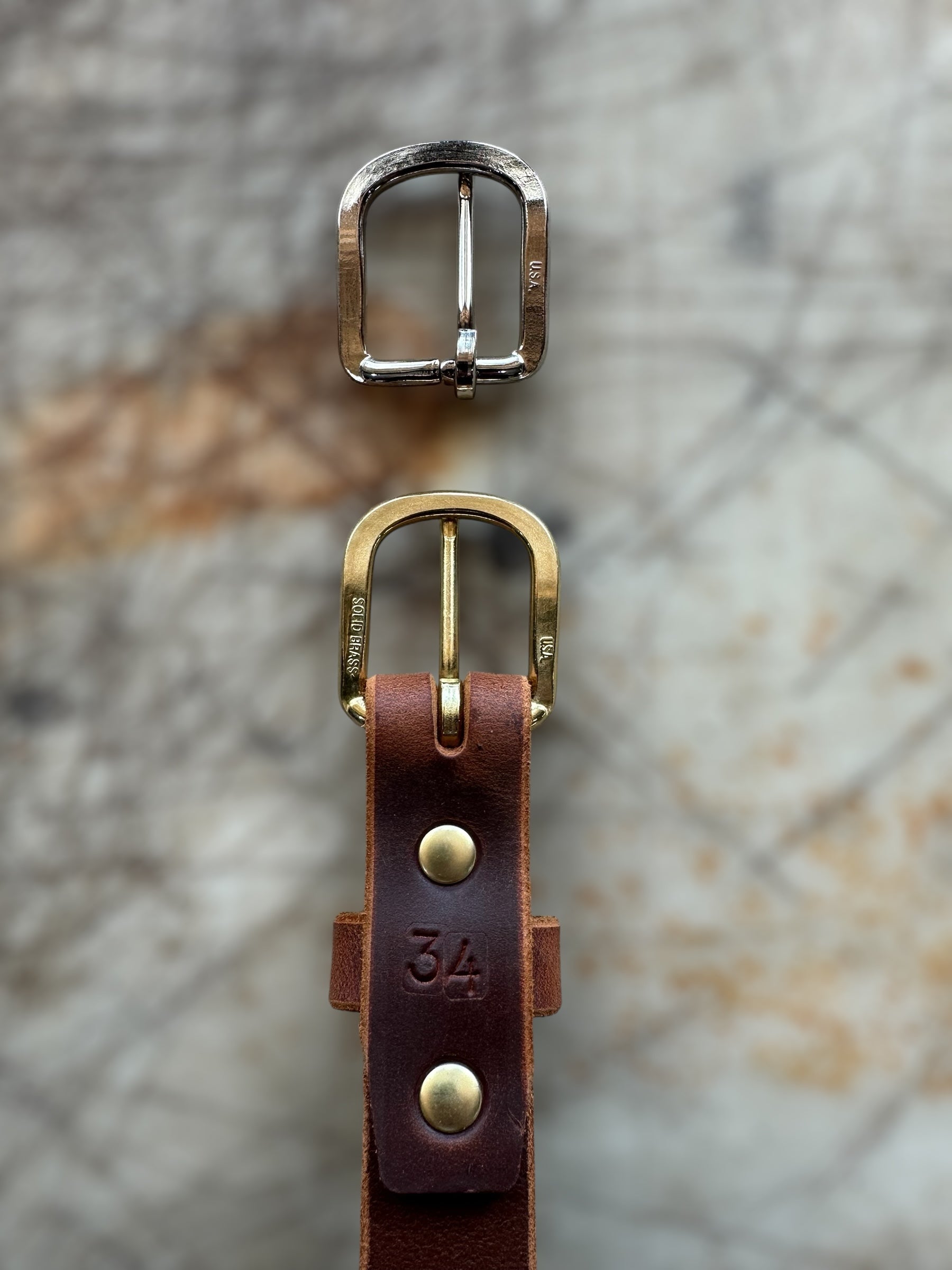 Brown leather belt with brass buckle on a textured surface