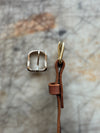 Gold buckle and brown leather strap on a textured stone background