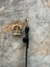 Gold buckle and black leather strap on a textured stone background