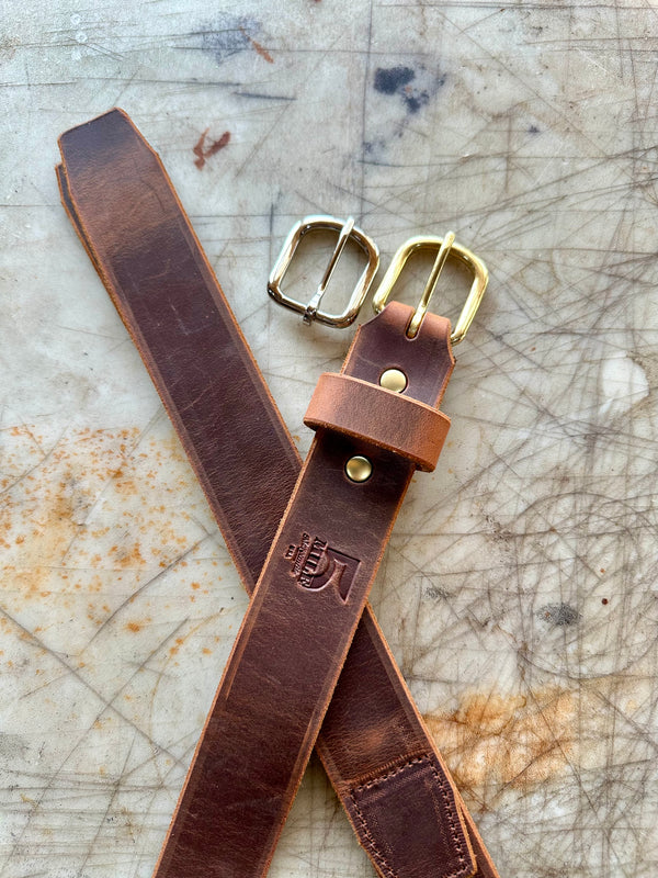Brown leather belt with brass  buckles on a textured surface