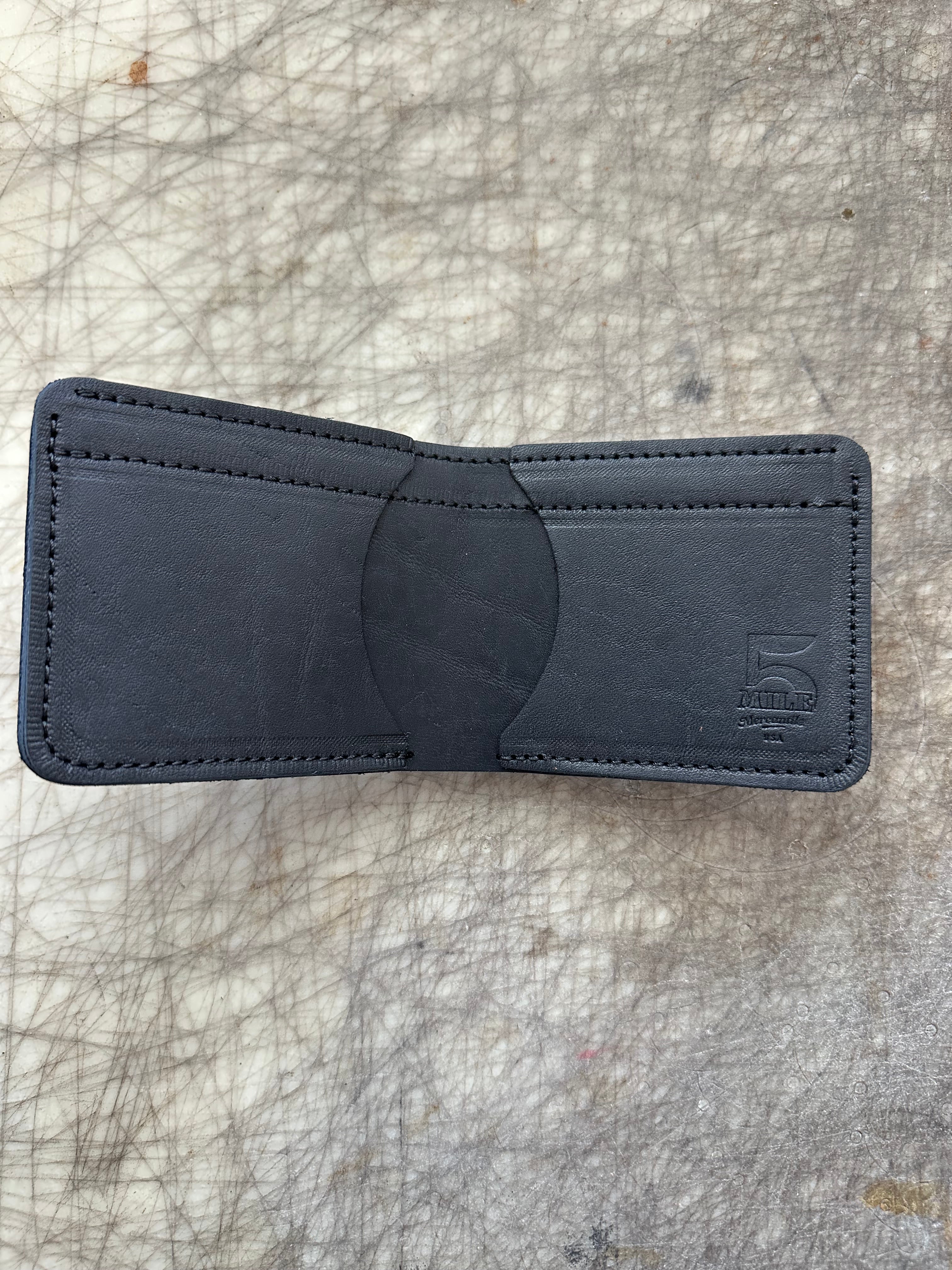 3 pocket bifold wallet black on cutting table