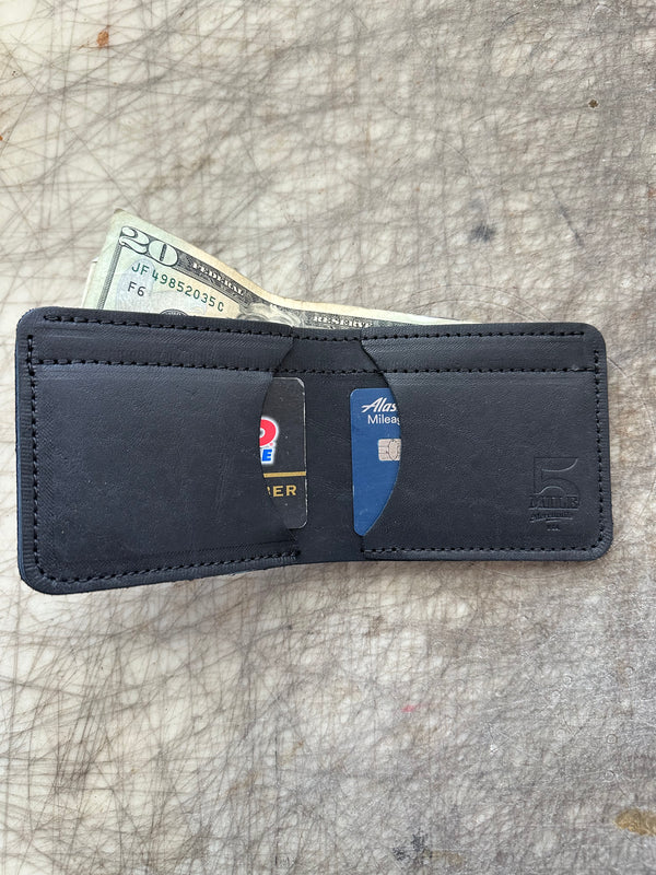 3 pocket bifold wallet black with cards and cash on cutting table