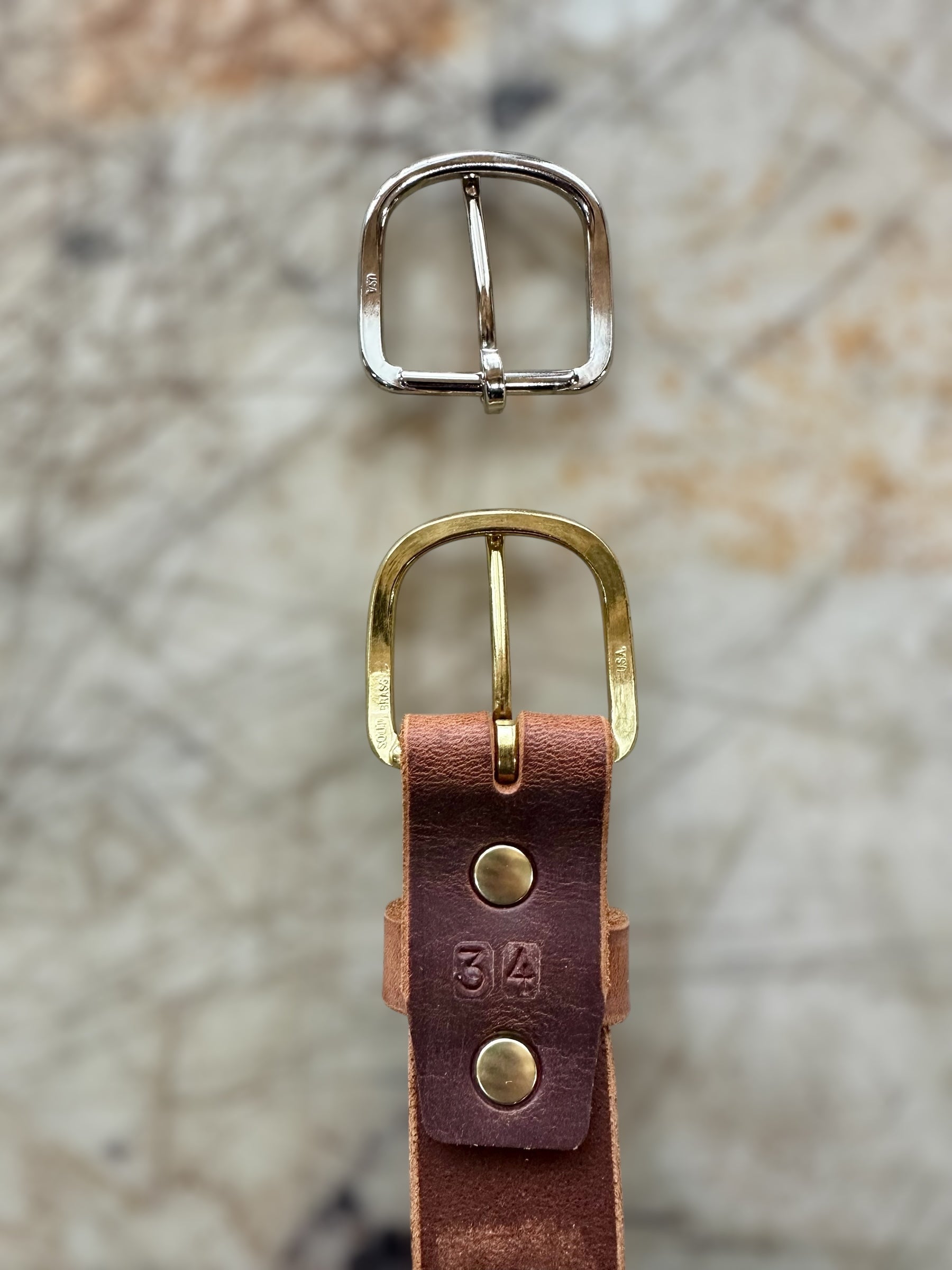 Gold and silver belt buckles on a textured surface