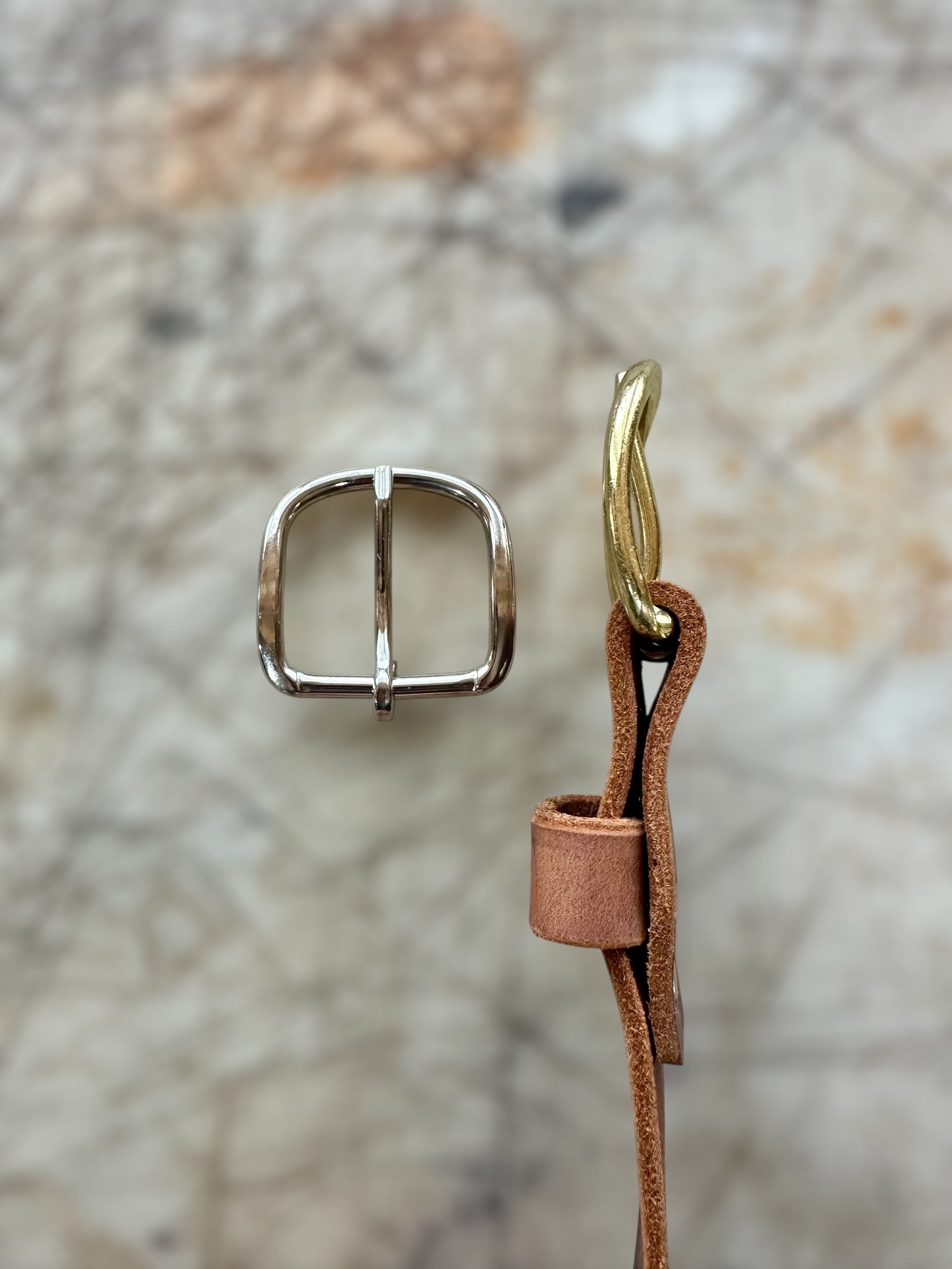 Metal buckle and leather strap on a textured surface