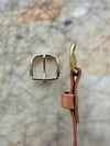 Metal buckle and leather strap on a textured surface