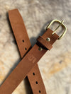 Brown leather belt with brass buckle on a textured surface