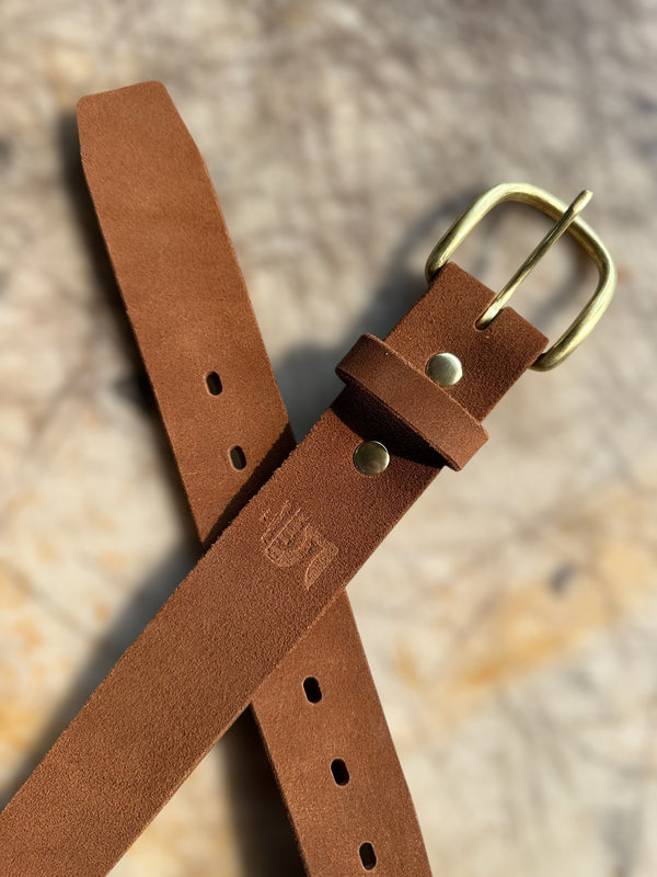 Brown leather belt with brass buckle on a textured surface