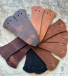 Set of leather samples in various colors arranged in a fan-like pattern on a textured surface.