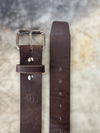 Brown belt with silver buckle on cutting table showing both ends of the belt