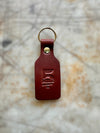 Brown leather keychain with a gold ring on a textured surface