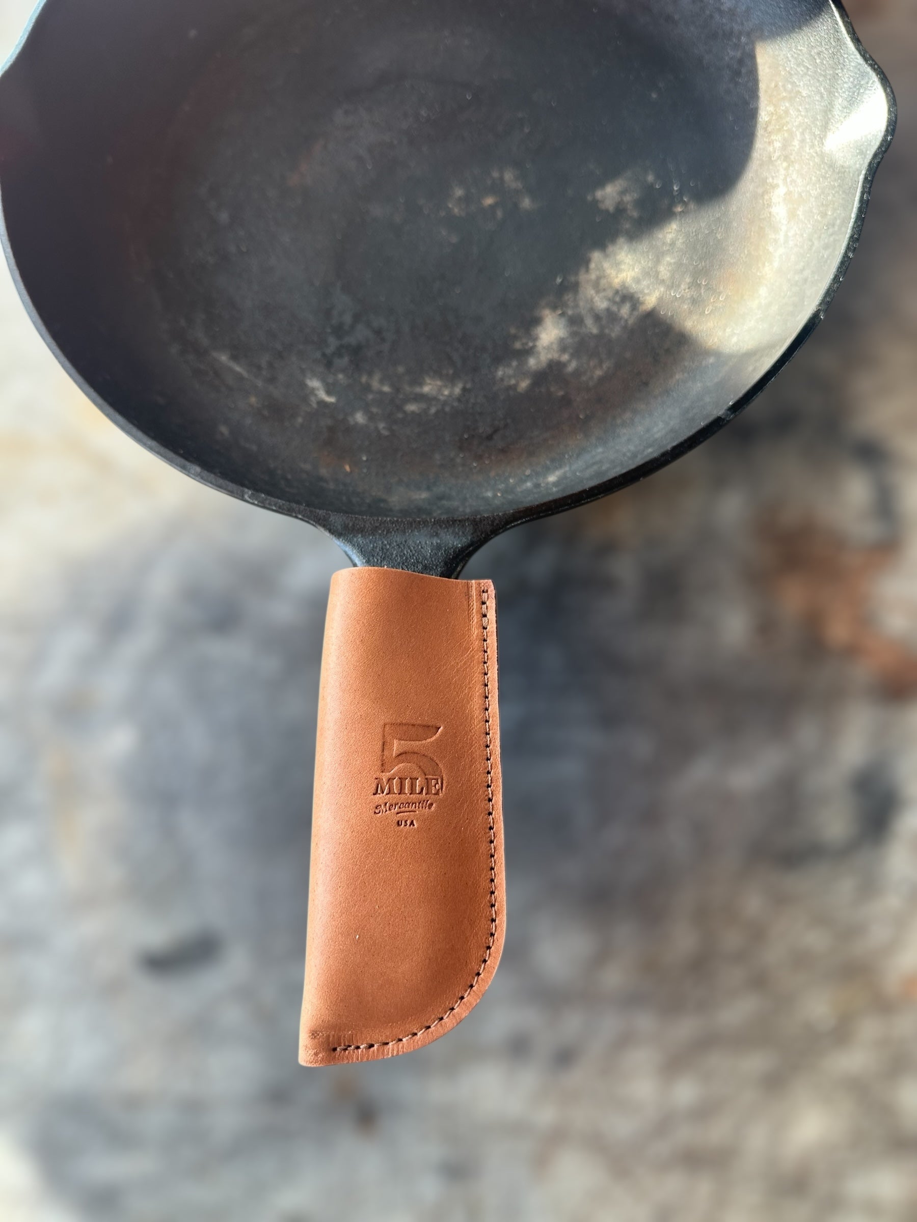 Cast iron skillet with a leather handle on a blurred background