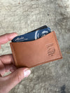 Brown leather wallet with card holder held by a hand on a textured surface