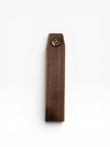 A dark brown leather strap or key fob sleeve with a single brass snap button closure, shown vertically on a clean white background.