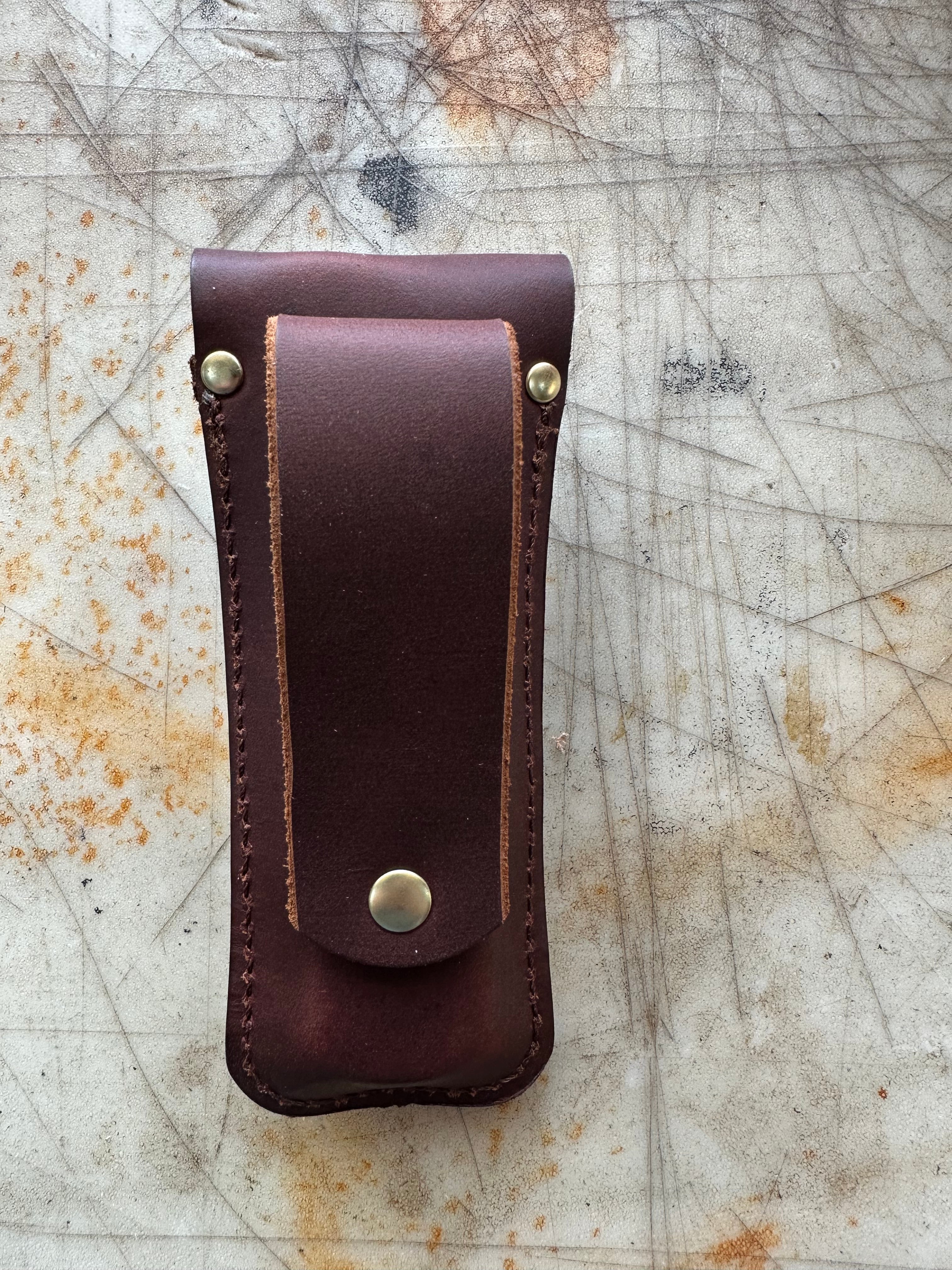 Back of Brown leather knife sheath on a textured surface