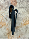 Black leather knife sheath with brass fasteners on a textured surface side profile