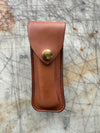 Brown leather pouch with a brass Snap on a textured surface