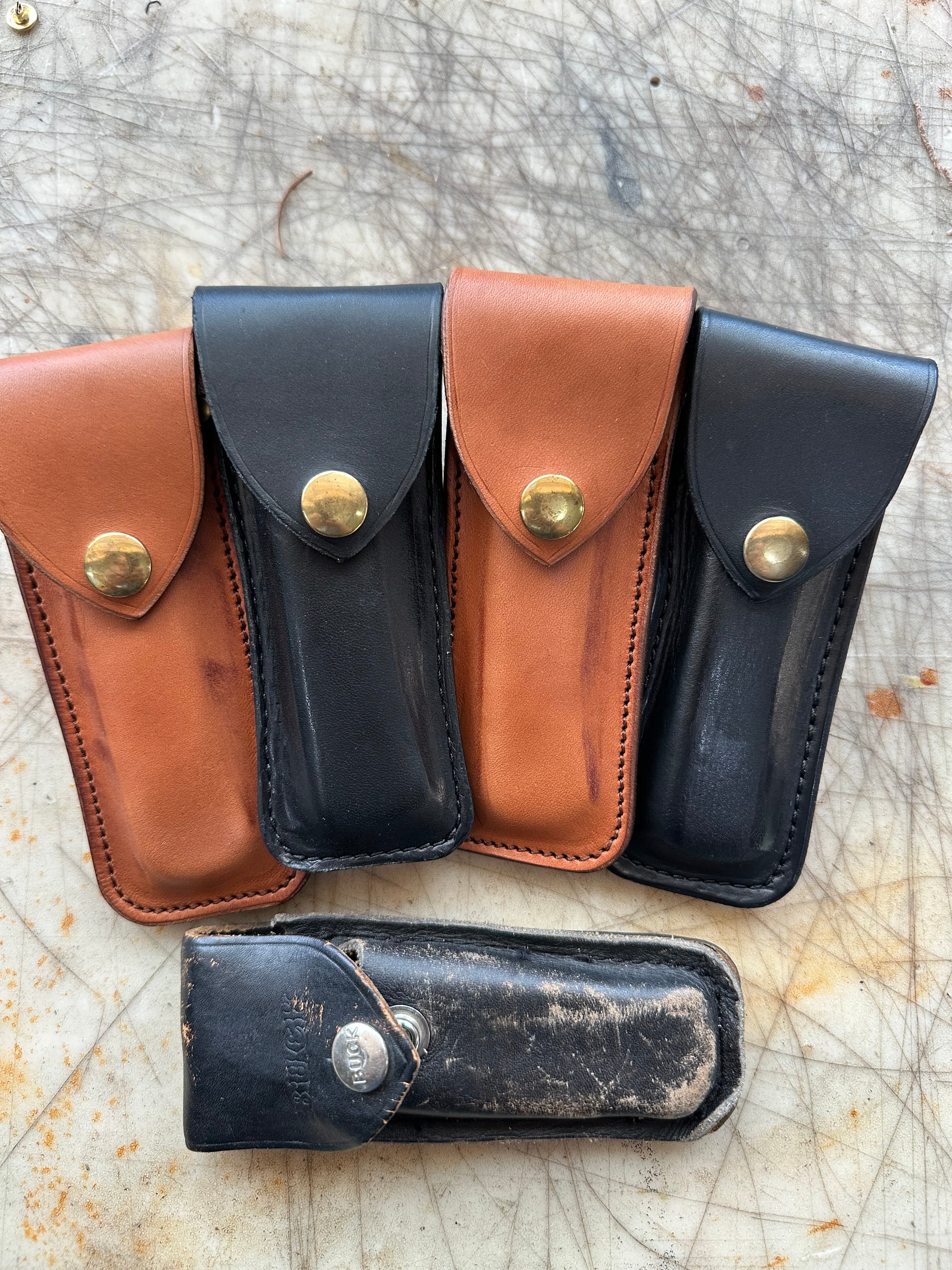 Collection of leather sheaths in black and brown on a textured surface