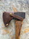 Camp axe with brown sheath snapped on cutting table