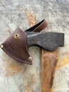 Camp axe with brown sheath unsnapped on cutting table