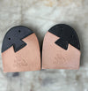 A pair of Cat's Paw heel caps for shoes, featuring a natural tan leather lower section with an embossed cat logo and brand name, and a black textured upper section.