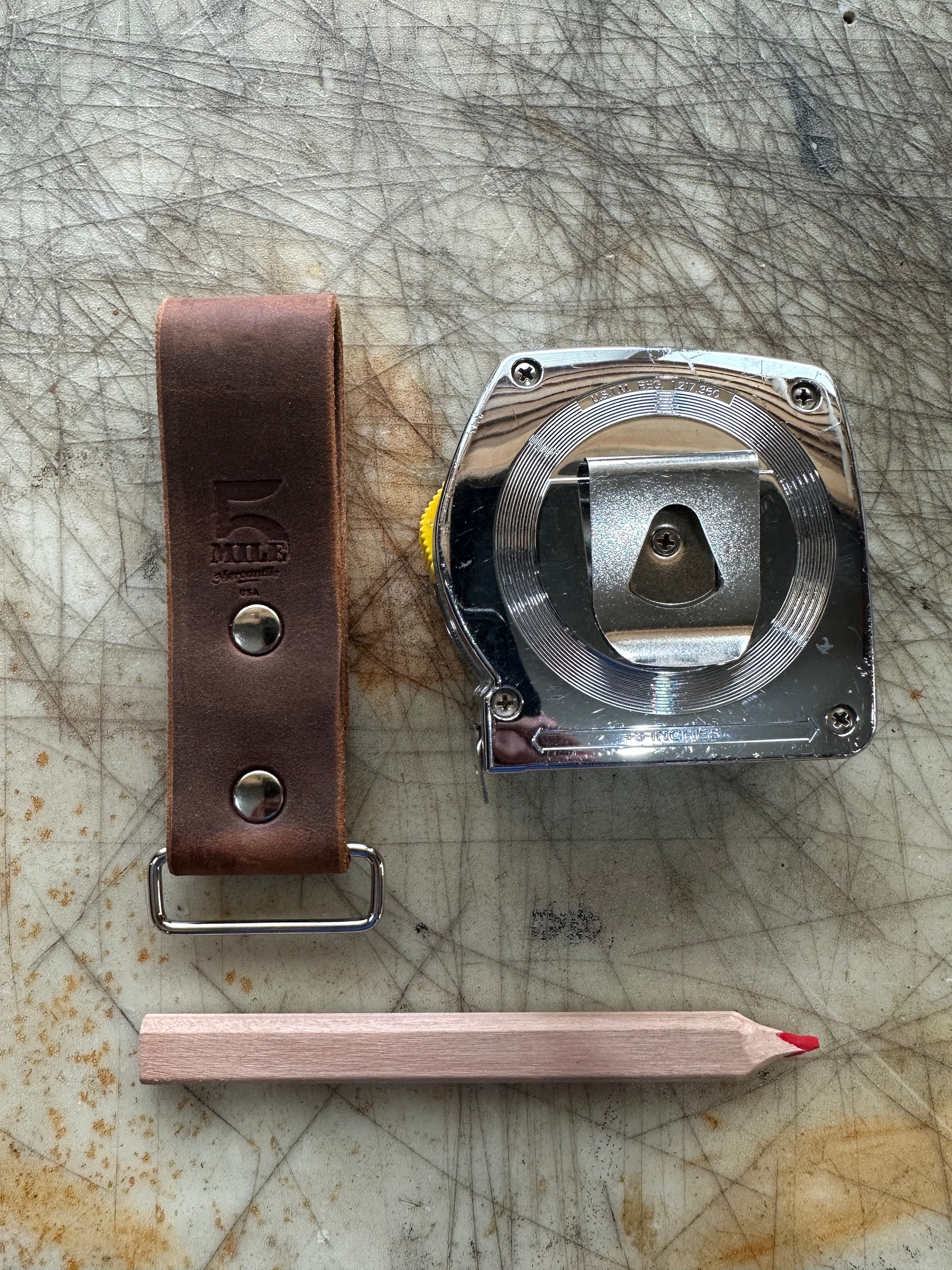 Mechanical component, leather belt, and pencil on a textured surface