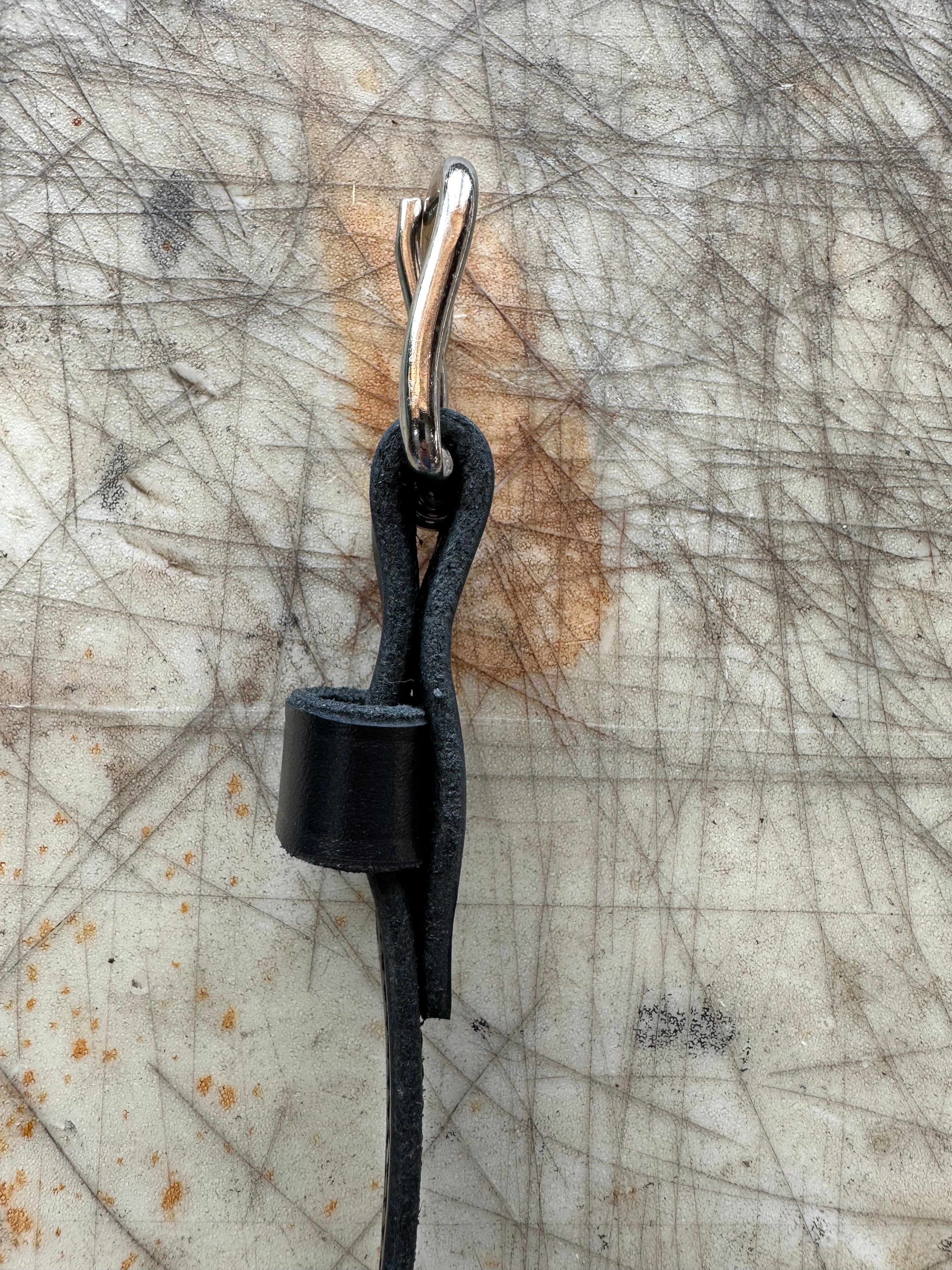 Close-up of a black leather belt with a silver buckle on a textured surface