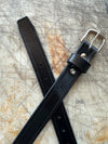 Black leather belt with silver buckle on a textured surface