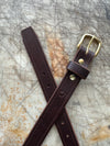 Brown leather belt with brass buckle on a textured surface