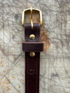 Brown leather belt with brass buckle on a textured surface
