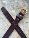 Brown leather belt with brass buckle on a textured surface