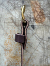 Side profile of brown belt with brass buckle on cutting board