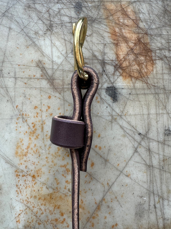 Side profile of brown belt with brass buckle on cutting board