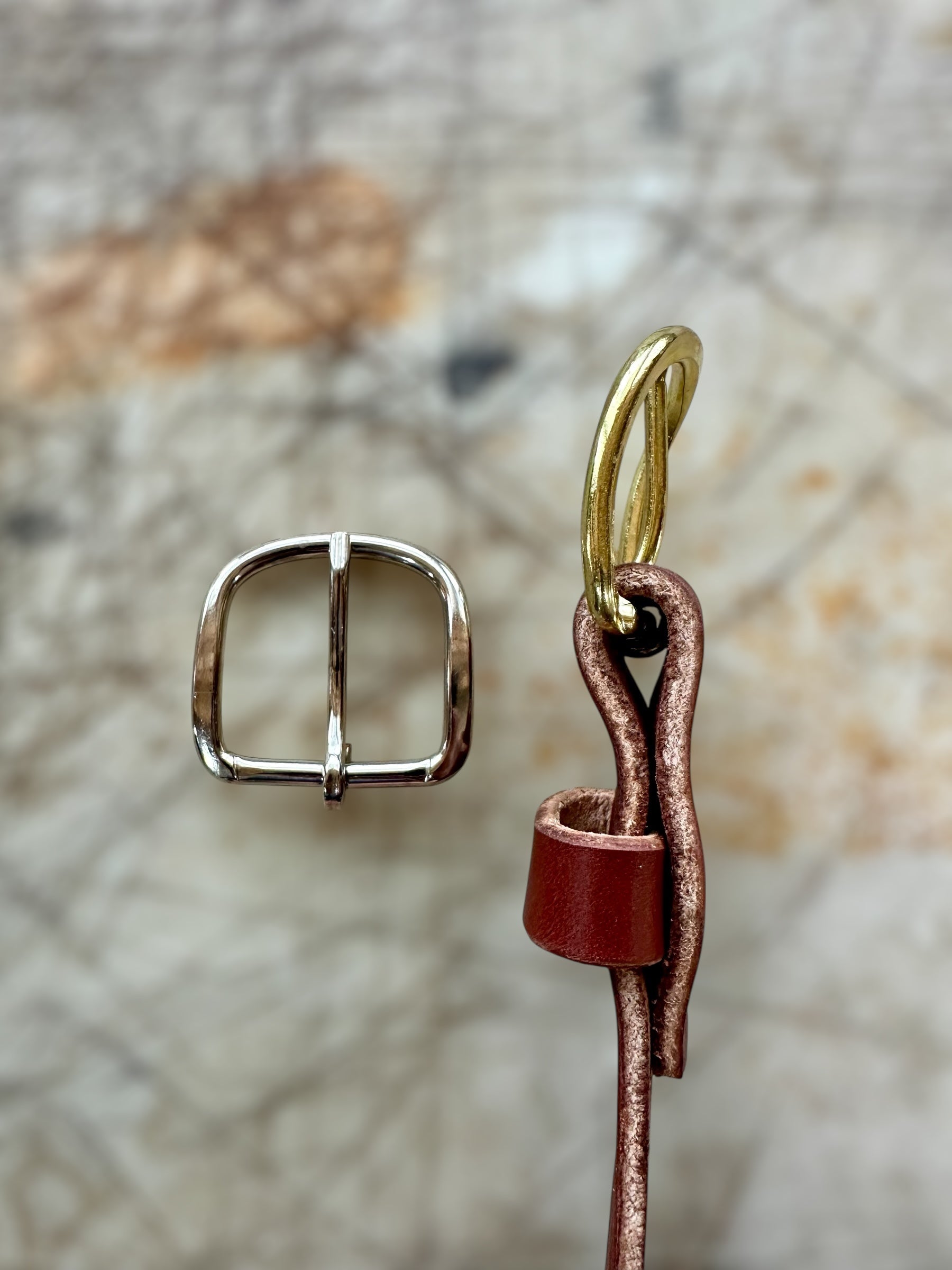 Metal buckle and leather strap on a textured stone background