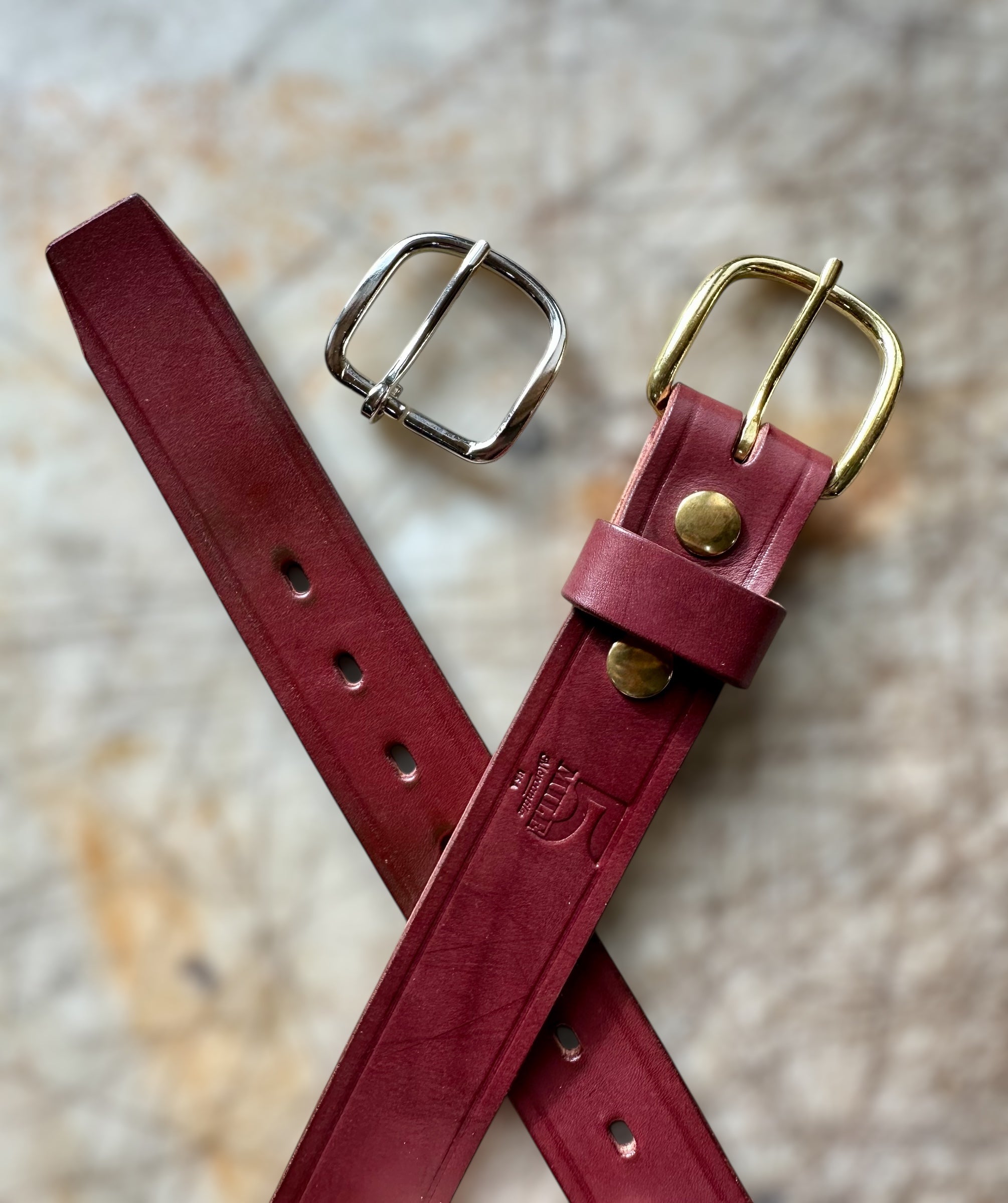 Two red leather straps with metal buckles on a textured surface