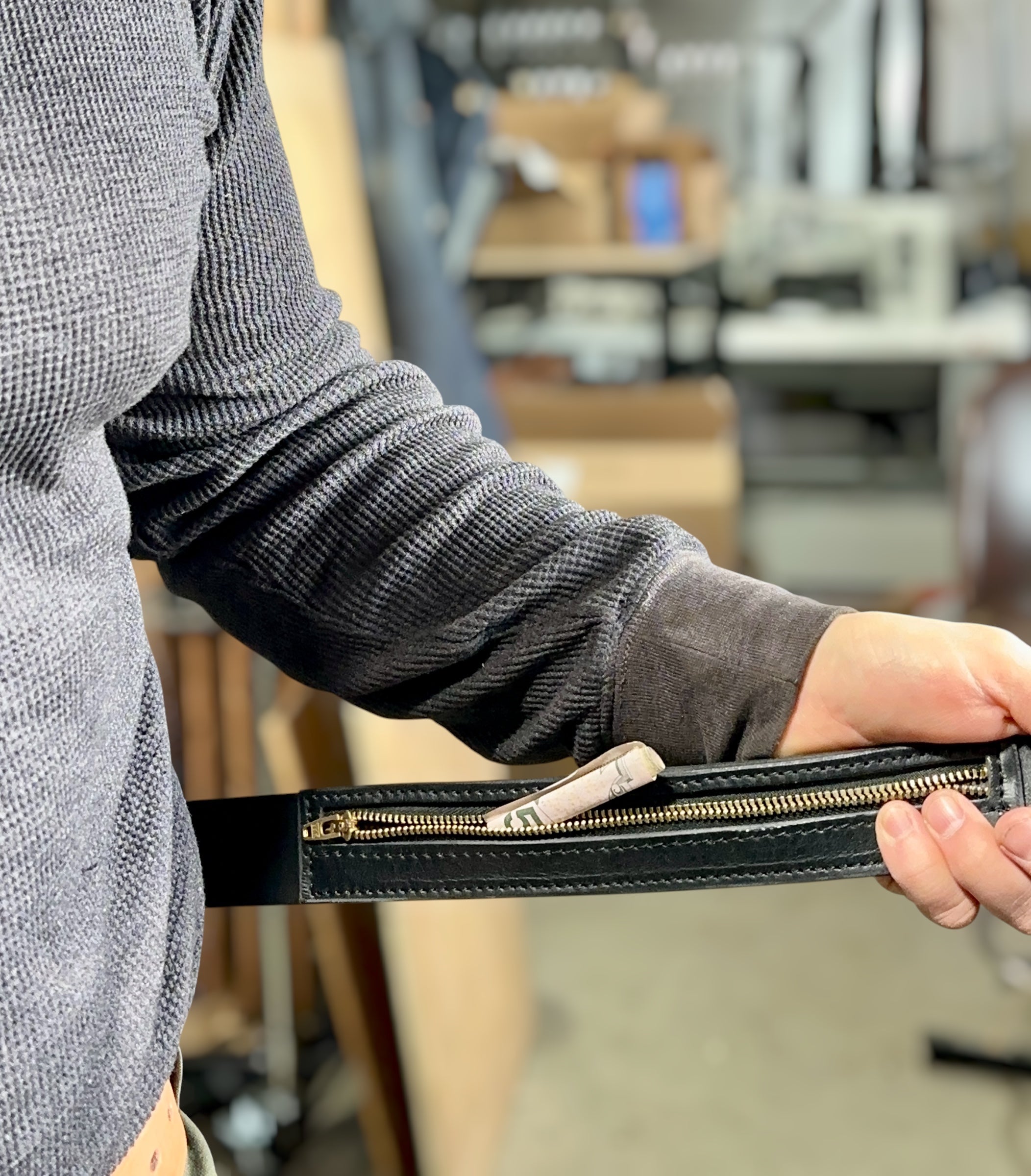 Person holding a black wallet with a blurred indoor background
