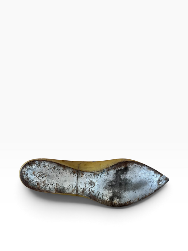 A single metallic shoe sole, likely from a vintage or distressed pair of high-heeled pumps, displayed horizontally against a plain white background.