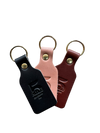 Three leather keychains in black, pink, and brown on a white background