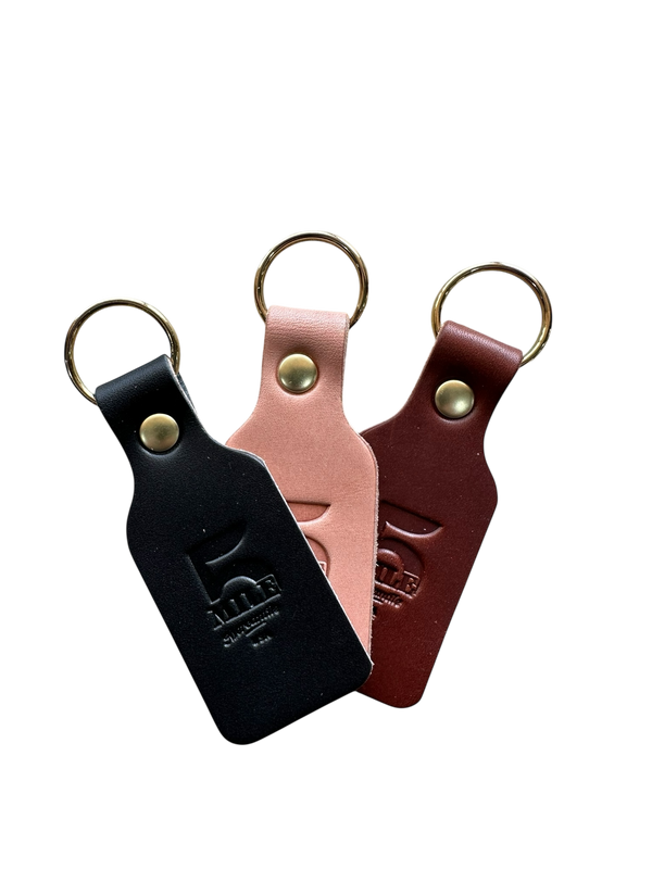 Three leather keychains in black, pink, and brown on a white background