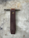 Brown leather pen holder with a pen on a marble surface