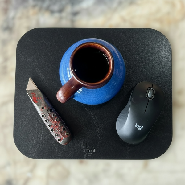 Blue mug with brown interior, knife, and Logitech mouse on a black mouse pad.