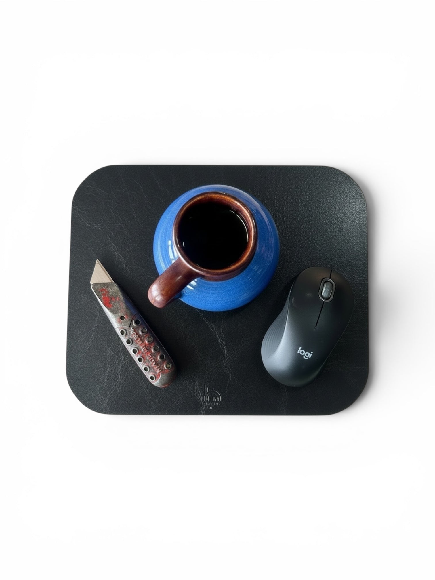 Blue mug with brown handle, remote control, and computer mouse on a black mouse pad.