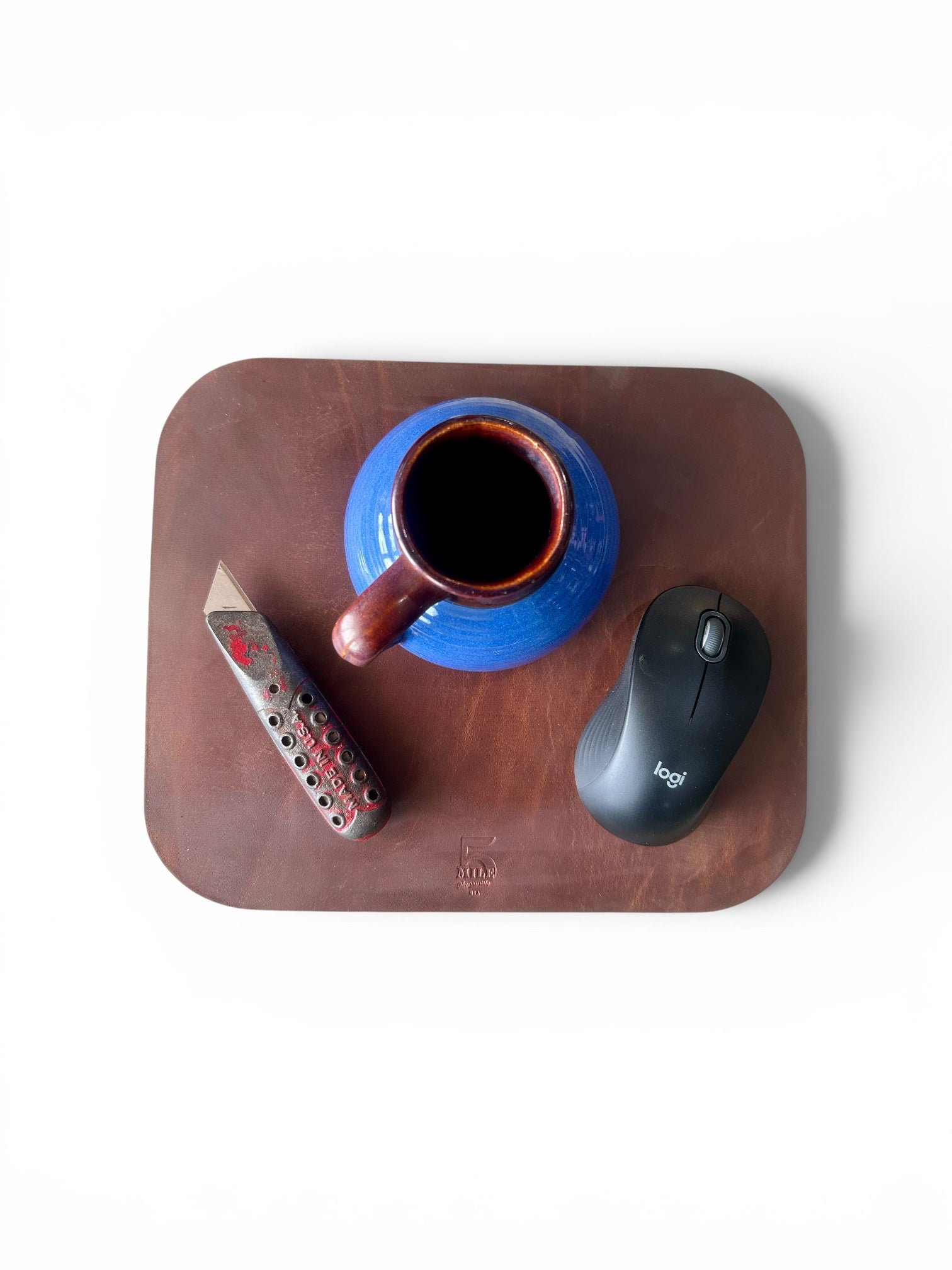 Blue mug with brown handle on a wooden tray, accompanied by a remote control and computer mouse.