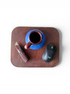 Blue mug with brown handle on a wooden tray, accompanied by a remote control and computer mouse.